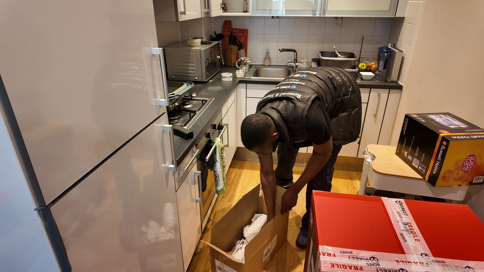 Crew member packing fragile boxes in kitchen with professional materials